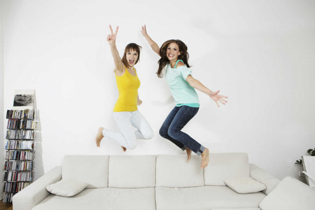 germany-berlin-young-women-having-fun-and-jumping-on-couch-SKF001015.jpg